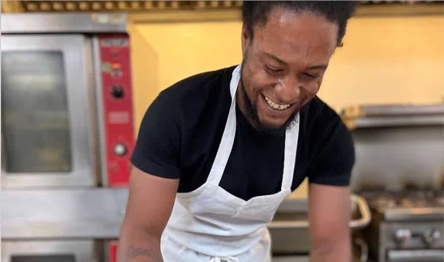 a man in an apron is smiling in a kitchen